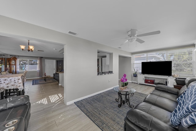 living room featuring sink and ceiling fan with notable chandelier