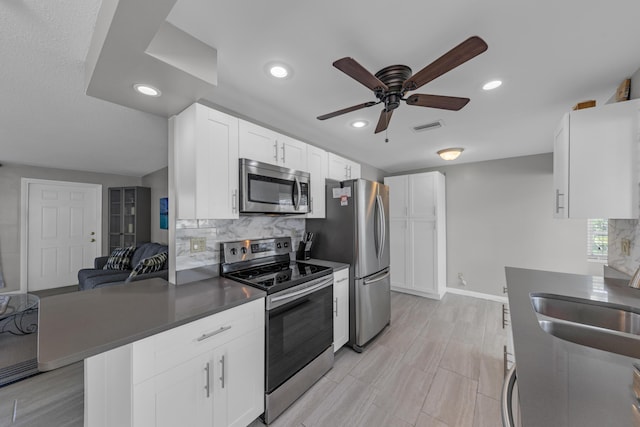 kitchen featuring sink, white cabinets, backsplash, ceiling fan, and stainless steel appliances