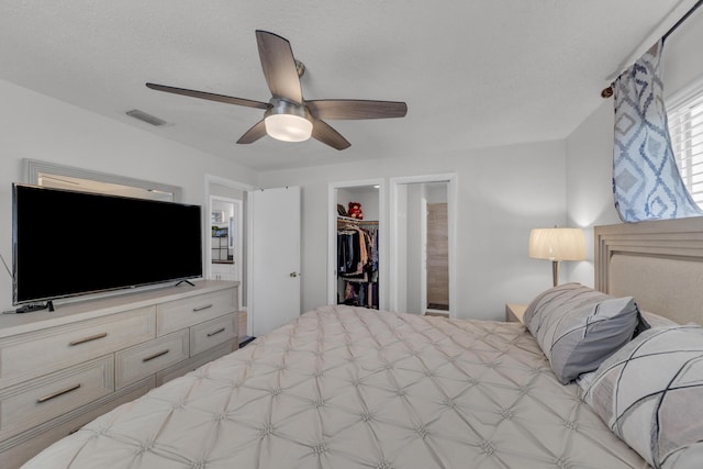 bedroom featuring a spacious closet, ceiling fan, a textured ceiling, ensuite bath, and a closet