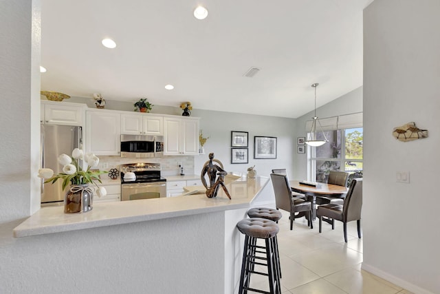 kitchen with tasteful backsplash, vaulted ceiling, appliances with stainless steel finishes, kitchen peninsula, and white cabinets