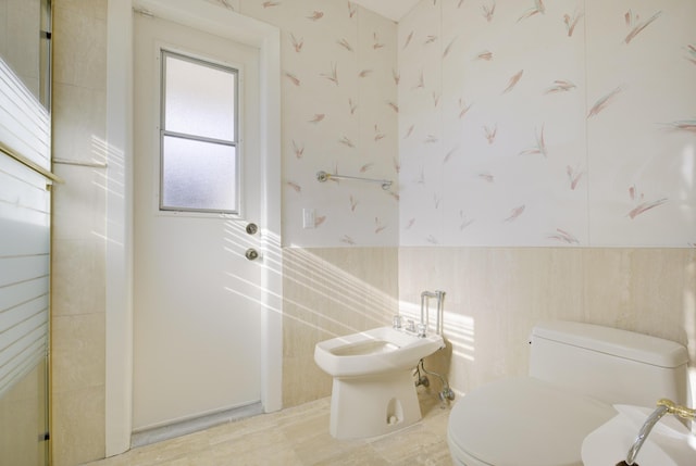 bathroom featuring a bidet, tile walls, and toilet