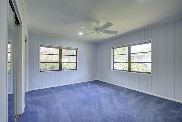 carpeted empty room with a wealth of natural light, ornamental molding, and ceiling fan