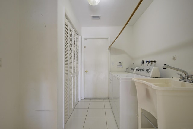 laundry area featuring light tile patterned floors, washing machine and dryer, and sink