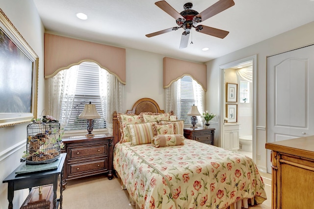 bedroom with light carpet, ceiling fan, and ensuite bath