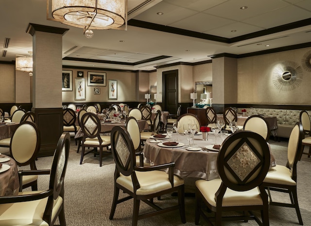 dining area featuring crown molding, decorative columns, a raised ceiling, and carpet flooring