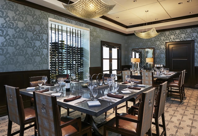 carpeted dining room featuring a raised ceiling and ornamental molding