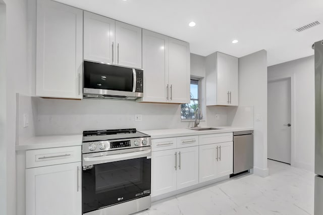 kitchen with appliances with stainless steel finishes, sink, and white cabinets