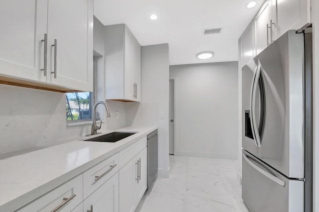 kitchen with sink, appliances with stainless steel finishes, backsplash, light stone countertops, and white cabinets