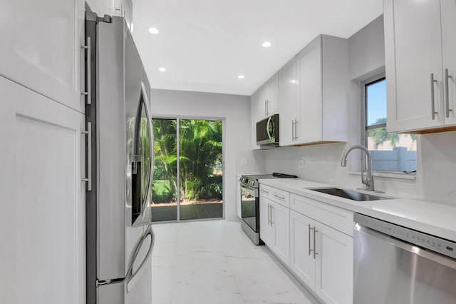 kitchen with white cabinetry, appliances with stainless steel finishes, sink, and backsplash