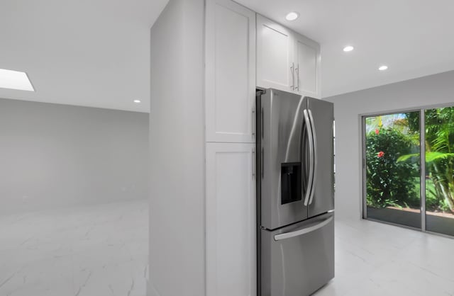 kitchen with stainless steel fridge, a skylight, and white cabinets