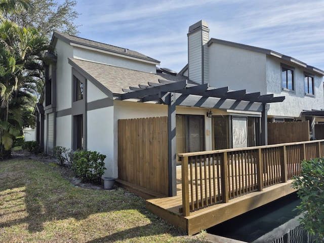 back of property featuring a pergola, a lawn, and a deck