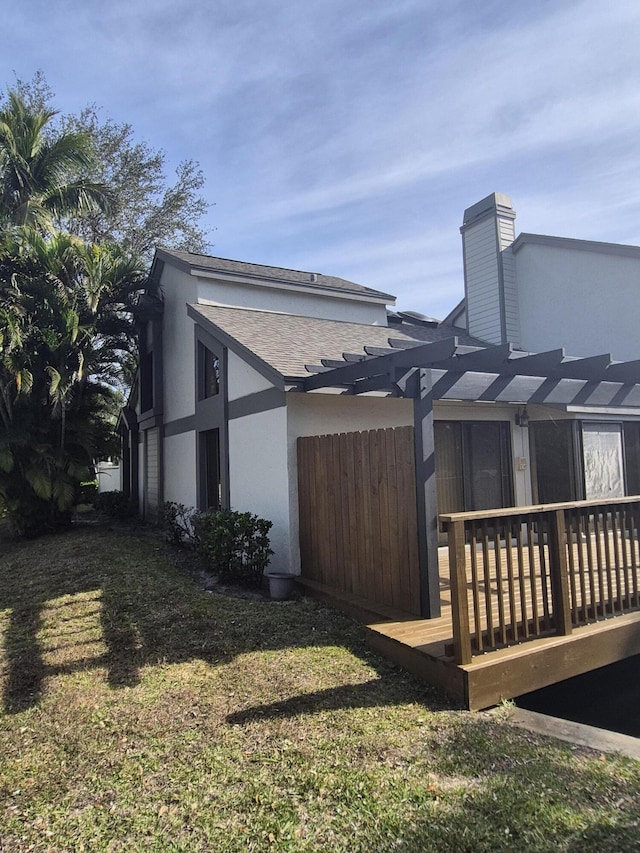 view of side of property featuring a pergola, a wooden deck, and a yard