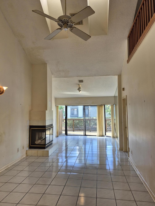 unfurnished living room with plenty of natural light, a high ceiling, a tile fireplace, and light tile patterned floors