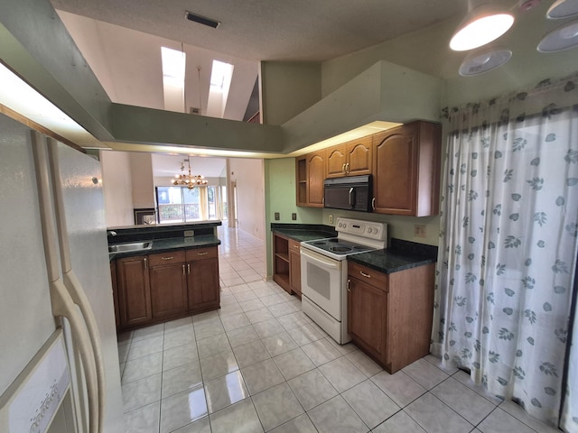 kitchen with sink, an inviting chandelier, high vaulted ceiling, light tile patterned floors, and white appliances