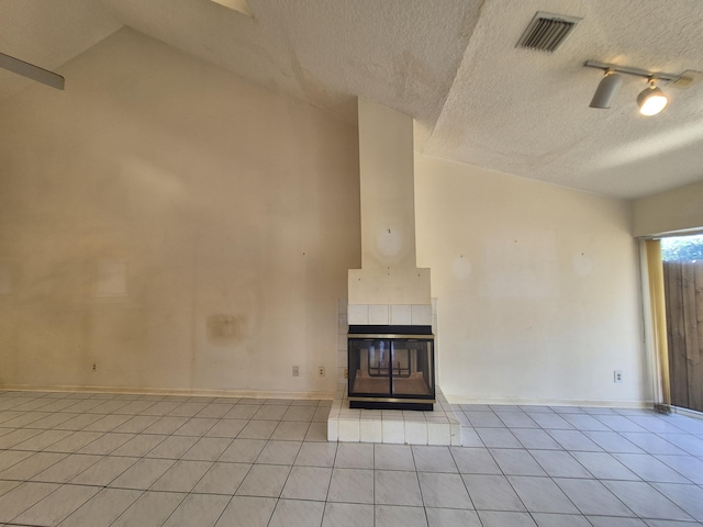 unfurnished living room featuring lofted ceiling, light tile patterned floors, a fireplace, and a textured ceiling