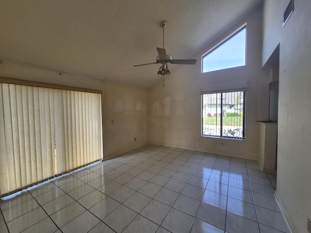 tiled empty room featuring ceiling fan, high vaulted ceiling, and a textured ceiling