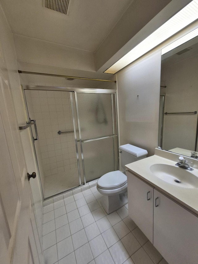 bathroom with vanity, toilet, tile patterned floors, and a shower with shower door