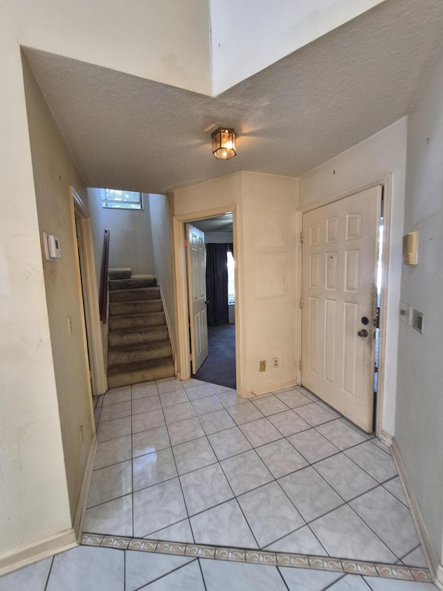 foyer with light tile patterned floors and a textured ceiling