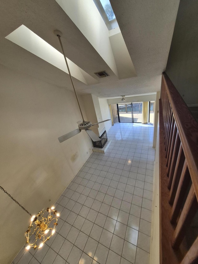 hall featuring light tile patterned floors and lofted ceiling with skylight