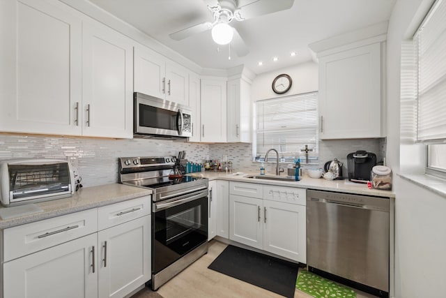 kitchen featuring sink, white cabinets, backsplash, light hardwood / wood-style floors, and stainless steel appliances