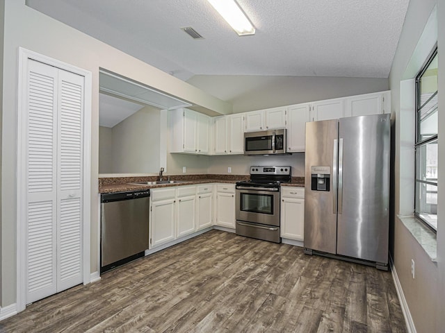 kitchen with stainless steel appliances, lofted ceiling, white cabinets, and dark hardwood / wood-style flooring