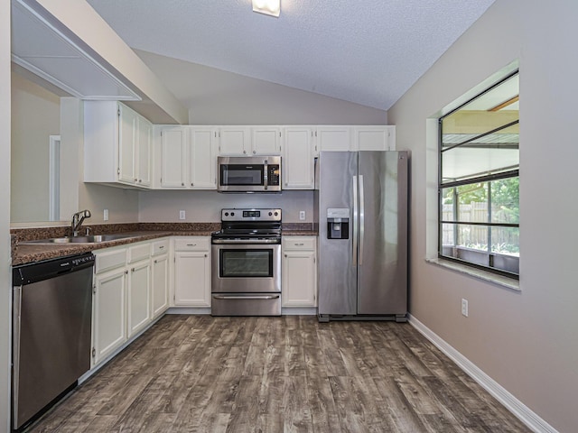 kitchen featuring sink, white cabinetry, vaulted ceiling, appliances with stainless steel finishes, and dark hardwood / wood-style floors