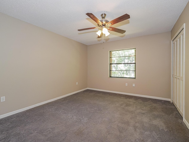 unfurnished bedroom with dark colored carpet, a textured ceiling, ceiling fan, and a closet