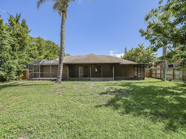 back of property with a yard and a lanai