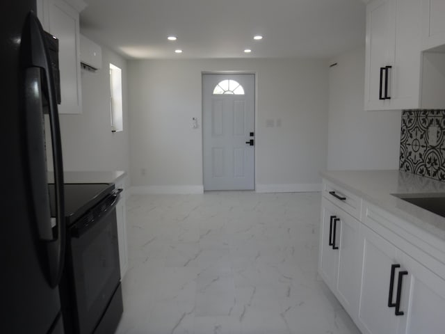 kitchen featuring white cabinetry, backsplash, and black appliances