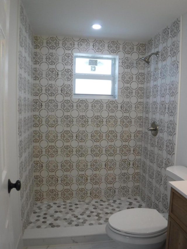 bathroom featuring vanity, a tile shower, and toilet