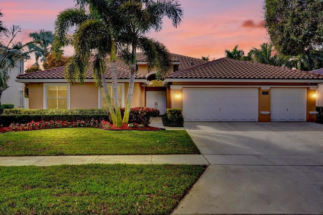 mediterranean / spanish-style home with a garage and a lawn