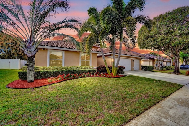 mediterranean / spanish-style house featuring a garage and a yard