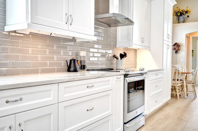 kitchen with light stone counters, stainless steel electric stove, white cabinets, and island exhaust hood