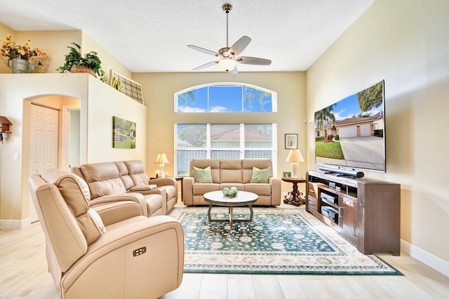 living room with ceiling fan, light hardwood / wood-style floors, and a textured ceiling