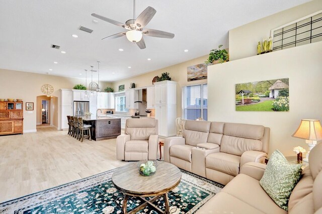 living room with ceiling fan, plenty of natural light, sink, and light wood-type flooring