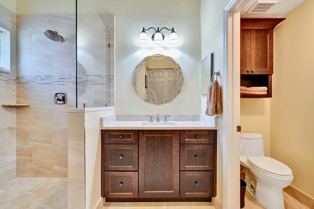 bathroom with vanity, toilet, and tiled shower