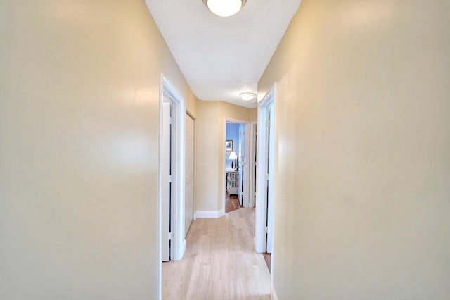 corridor with light hardwood / wood-style flooring and a textured ceiling