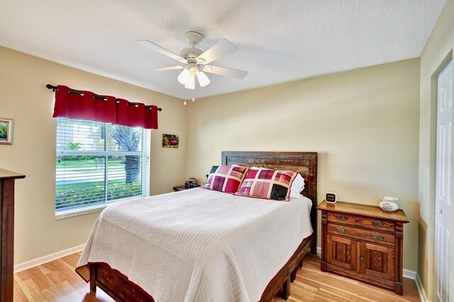 bedroom with a textured ceiling, light hardwood / wood-style flooring, and ceiling fan