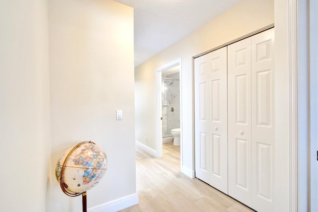 hallway featuring light hardwood / wood-style floors and a textured ceiling