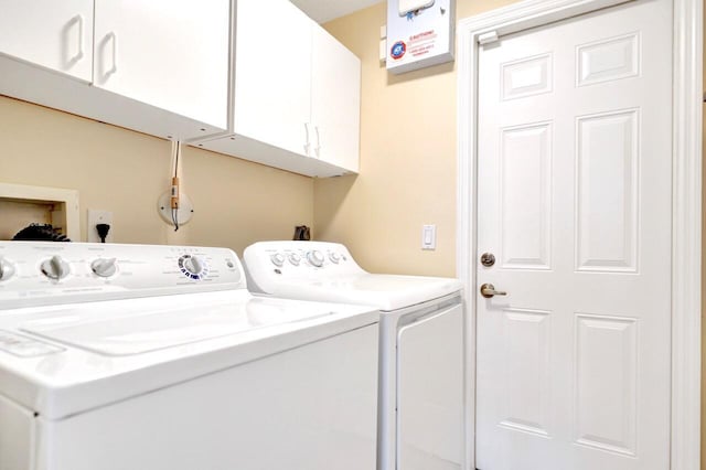 clothes washing area with cabinets and washing machine and dryer