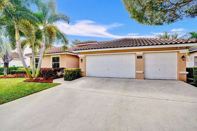 mediterranean / spanish home featuring a garage and a front lawn