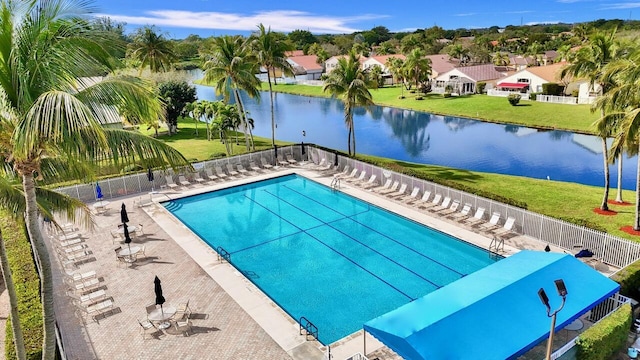 view of swimming pool with a water view, a patio, and a lawn