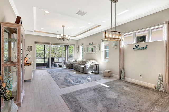 unfurnished living room with ornamental molding, a tray ceiling, hardwood / wood-style floors, and a notable chandelier