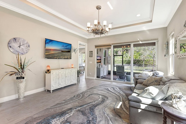 living room featuring a notable chandelier, crown molding, a raised ceiling, and hardwood / wood-style flooring