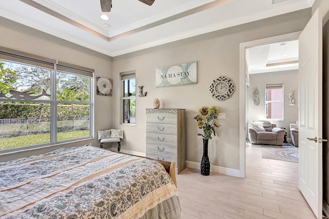 bedroom featuring ornamental molding, a raised ceiling, and light wood-type flooring