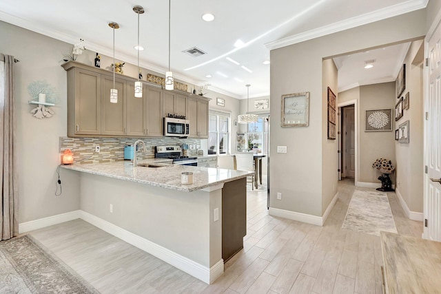 kitchen with hanging light fixtures, light stone countertops, appliances with stainless steel finishes, and kitchen peninsula