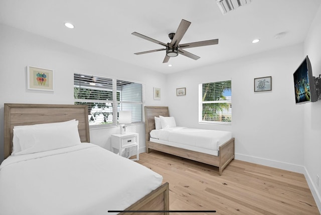 bedroom with multiple windows, ceiling fan, and light wood-type flooring