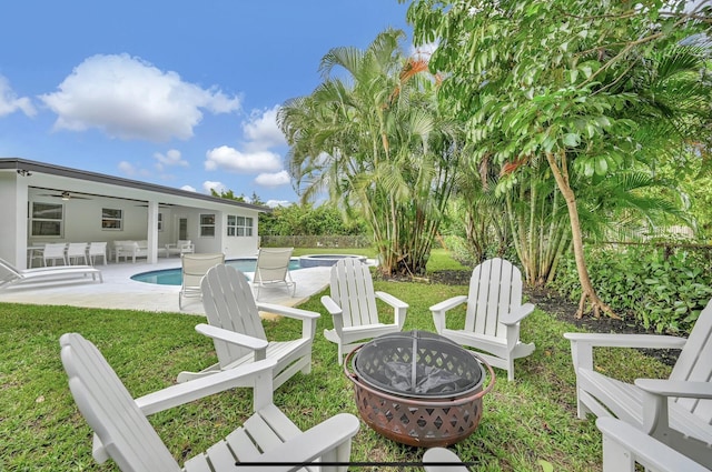 view of yard with a fenced in pool, a patio, ceiling fan, and an outdoor fire pit