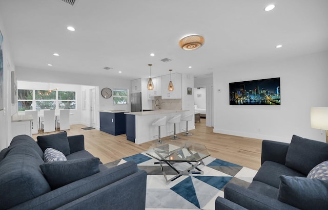 living room featuring a wealth of natural light, sink, and light wood-type flooring