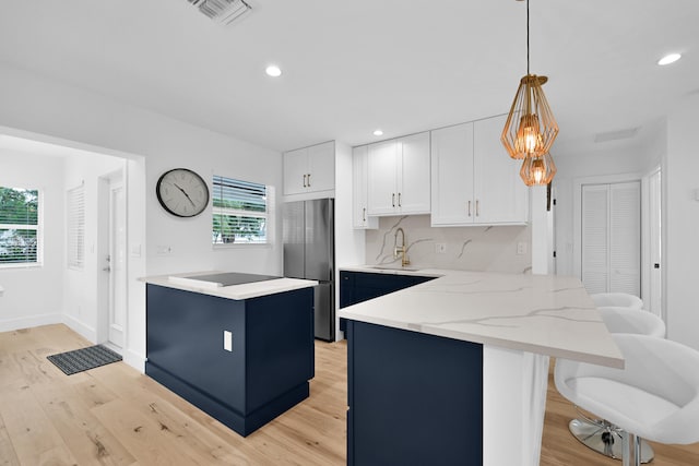 kitchen featuring hanging light fixtures, white cabinetry, a wealth of natural light, and stainless steel fridge